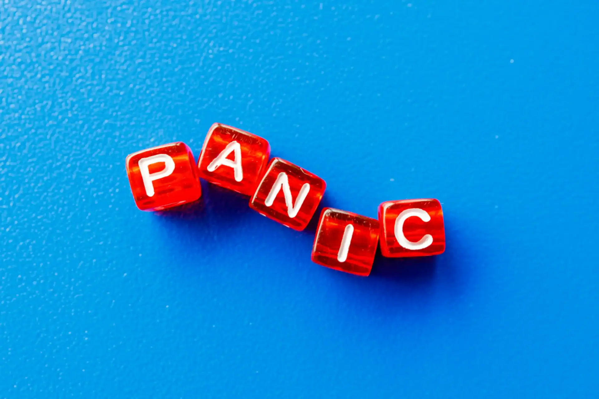 Rote Würfel bilden das Wort PANIC auf blauem Hintergrund als Symbol für Panik beim Kinderwunsch